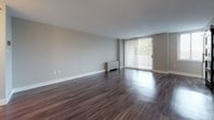 Located at 2000 Riverside Dr in Richmond, Virginia, this single-floor residence offers a clean, modern aesthetic throughout. Dark hardwood-style flooring runs consistently across the living areas and bedrooms, providing a rich contrast against the neutral gray walls and crisp white trim and baseboards.

The spacious living area is a standout feature, anchored by a large floor-to-ceiling sliding glass door fitted with vertical blinds that invite generous natural light and provide access to the outdoors. A radiator unit positioned beneath the window ensures year-round comfort.

The kitchen is thoughtfully designed with white cabinetry, granite-style countertops, a gray subway tile backsplash, and stainless steel appliances including a gas range and over-the-range microwave, offering both style and functionality.

The bedrooms are well-sized, featuring neutral gray walls, dark flooring, and ample closet space with panel-style bifold closet doors. Windows dressed with horizontal blinds allow natural light while maintaining privacy.

The bathroom is clean and functional, equipped with a full tub-and-shower surround in white, complemented by chrome fixtures. The overall layout, as seen in the dollhouse view, is efficient and well-connected, with clear sightlines between the living area, kitchen, and bedrooms, creating a cohesive and comfortable living environment.