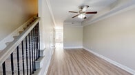 Located at 1521 Wilma Rudolph Blvd in Clarksville, Tennessee, this two-story, two-bedroom, two-bathroom home offers a well-organized layout across two distinct levels. The main floor features a bright, open living room with light hardwood-style flooring, crown molding, and a ceiling fan with light fixture. A staircase with elegant iron balusters and carpeted treads connects the floors. The dining area is bathed in natural light from large windows fitted with white blinds and is accented by a modern chandelier. The kitchen is outfitted with rich dark cabinetry, granite countertops, stainless steel appliances including a refrigerator, dishwasher, and microwave, along with a dedicated pantry. A full bathroom with hardwood-style flooring is also located on this level. Upstairs, both bedrooms feature plush carpet, ceiling fans, and ample natural light. The spacious primary bedroom includes generous closet space. A second full bathroom and a convenient laundry area round out the upper floor. The home also includes a balcony, four closets throughout, and a neutral, warm color palette that creates a welcoming atmosphere throughout.