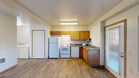 Located at 3601 NE 162nd Ave in Portland, Oregon, this single-floor, one-bedroom, one-bathroom unit offers a practical and well-organized layout. The open-concept living, dining, and kitchen area forms the heart of the unit, finished with durable wood-look flooring that extends throughout. The kitchen is equipped with warm honey-toned oak cabinetry providing ample upper and lower storage, a full suite of white appliances including a refrigerator, electric range, and dishwasher, complemented by a double-basin sink and laminate countertops. A door with a window panel off the kitchen offers a private exterior entrance with natural light. The living and dining area provides a functional open space suitable for both relaxing and entertaining. The bedroom features plush wall-to-wall carpeting, a window with vertical blinds allowing natural light, and a sliding-door closet with a built-in rod for convenient storage. The bathroom includes a full tub-shower combination finished with clean white tile surround. Additional practical spaces include a dedicated laundry area and a utility room. Neutral wall tones and textured ceilings are consistent throughout, lending the unit a clean, move-in-ready appearance.