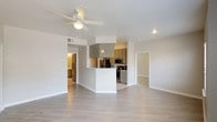 This single-story residence offers a thoughtfully designed layout across two bedrooms and two full bathrooms. The open-concept living and dining area is finished with light wood-look flooring and neutral gray-toned walls, creating a clean, cohesive aesthetic. A ceiling fan with integrated lighting anchors the living space, while multiple windows invite ample natural light, enhancing the airy feel of the room.

The kitchen is positioned adjacent to the living area behind a peninsula-style half-wall, providing a natural separation while maintaining an open flow. It features gray cabinetry, light countertops, subway tile backsplash, tile flooring, and a full suite of stainless steel appliances, including a refrigerator, range, microwave, and dishwasher.

Both bedrooms continue the wood-look flooring and are equipped with ceiling fans. The primary bedroom benefits from multiple windows and access to a walk-in closet outfitted with built-in shelving and hanging rods. Each bathroom includes gray vanity cabinetry, a large mirror, a vanity light bar, and tile flooring, maintaining a consistent, modern design language throughout the home.