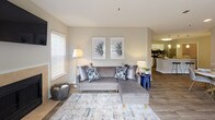 Located at 1500 Sunbow Falls Ln in Raleigh, NC, this single-story residence offers a thoughtfully designed layout with comfortable living spaces and modern finishes throughout. The open-concept living room is a standout feature, showcasing wood-look flooring, a tiled fireplace, and a sliding glass door that opens to a private balcony, filling the space with natural light. The kitchen is well-equipped with white shaker-style cabinetry, granite countertops, a dark subway tile backsplash, stainless steel appliances, and a peninsula island with bar seating — ideal for casual dining and entertaining. Pendant lighting adds a refined touch overhead. A dedicated laundry area with a full-size washer and dryer is conveniently accessible from the kitchen. The bedrooms are carpeted for comfort, each offering natural light from large windows. The primary bedroom includes an en-suite bathroom featuring a granite-topped vanity with white cabinetry, wood-look flooring, and a well-lit mirror. A second bedroom provides equally comfortable accommodations. Neutral tones, clean lines, and consistent finishes create a cohesive and inviting ambiance throughout the entire residence.