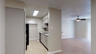 Located at 6803 N Navarro St in Victoria, Texas, this single-floor unit offers a functional and well-appointed layout throughout. The living area features warm wood-look laminate flooring, neutral-toned walls, and a ceiling fan with integrated lighting. Vertical blinds cover a sliding glass door that allows natural light to fill the space. The open pass-through connects the living area to the kitchen, enhancing the sense of flow between rooms. The galley-style kitchen is efficiently designed with gray shaker-style cabinetry, granite-look countertops, a mosaic tile backsplash, and black appliances including a refrigerator, range, and built-in microwave. A stainless steel sink and dishwasher complete the kitchen's practical features, with a skylight-style ceiling fixture providing overhead illumination. The bedrooms are finished with plush carpet flooring, ceiling fans, and windows with blinds that bring in natural light. One bedroom includes access to a walk-in closet and a private en-suite bathroom. The bathroom is finished with large-format gray tile, a granite-topped vanity with gray cabinetry, a soaking tub, and a well-lit mirror. Throughout the unit, consistent neutral tones and clean finishes create a cohesive and move-in-ready environment.