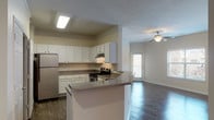 This upgraded two-bedroom, two-bathroom residence spans a generous single floor and features a well-appointed layout designed for comfortable everyday living. Dark hardwood-style flooring flows consistently throughout the main living areas and bedrooms, complemented by crisp crown molding and neutral-toned walls that create a clean, cohesive aesthetic.

The kitchen is efficiently designed with white cabinetry offering ample storage, speckled granite-style countertops, a double stainless steel sink, and a stainless electric range. A pass-through connection to the living area keeps the space feeling open and connected.

The main living area is bright and spacious, featuring a ceiling fan with light fixture and windows that bring in natural light with views of surrounding greenery. The open flow between the living and dining areas provides versatile arrangement options.

Both bedrooms are well-sized with dark hardwood-style floors, crown molding, and ceiling fans. The primary bedroom includes direct access to a private bathroom and a dedicated walk-in closet. The second bedroom also benefits from generous natural light through large windows.

The bathrooms are finished with wood-look flooring, white cabinetry with dark countertops, and a tub-shower combination with decorative tile accents. Overall, this residence delivers a polished, move-in-ready experience with upgraded finishes throughout.