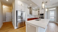 Located in the desirable Pinehurst Park neighborhood of Charlotte, NC, this well-appointed single-floor residence offers a thoughtfully designed layout with high-quality finishes throughout. The kitchen is a true centerpiece, showcasing a striking two-tone design with crisp white upper cabinetry and warm wood-toned lower cabinets, complemented by quartz countertops, a herringbone tile backsplash, and stainless steel appliances including a built-in wall oven, microwave, and refrigerator. A spacious island with an undermount sink and stylish pendant lighting adds both function and elegance. Light wood flooring flows through the main living and kitchen areas, creating a warm, cohesive feel. The bedrooms are carpeted and generously sized, each benefiting from large windows that invite abundant natural light and views of the surrounding community. The bathrooms are finished with large-format tile flooring and warm wood vanities topped with white countertops; one features a soaking tub and glass-enclosed shower, while another offers a dual-sink vanity. A dedicated laundry area with stacked washer and dryer and white cabinetry adds everyday convenience. Crown molding and recessed lighting complete the polished, move-in-ready aesthetic of this Charlotte home.