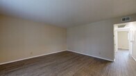 This single-story, 3-bedroom, 1-bathroom home offers a thoughtfully arranged layout that maximizes every square foot of available space. The living room serves as the heart of the home, featuring warm wood-look plank flooring and neutral beige walls that create a clean, inviting atmosphere. A front-facing window allows natural light to fill the entryway and living area, offering views of the surrounding greenery outside.

The kitchen is equipped with white cabinetry, dark granite-style countertops, a smooth-top electric range, and an overhead ventilation hood — providing a functional space for everyday cooking. The three bedrooms continue the consistent flooring found throughout the home and are finished with neutral tones. The primary bedroom benefits from a ceiling fan with integrated lighting, a window with outdoor views, and direct access to a dedicated walk-in closet featuring dual hanging rods and a built-in shelving unit for organized storage. Additional bedrooms include standard sliding-door closets with hanging rods.

The shared bathroom includes a combination tub and shower with a grab bar, a toilet, and a vanity with a dark countertop. A hallway connects the bedroom wing to the main living areas, completing the efficient and straightforward floor plan throughout this well-appointed home.