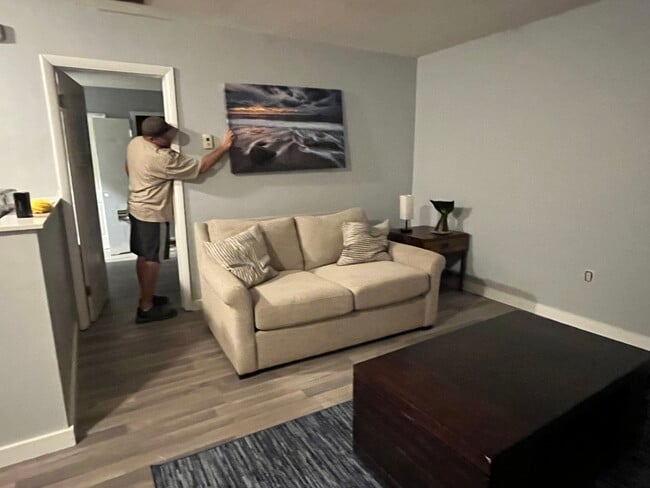 Comfy living room with mgr holding painting as we set it up - 5111 NE 18th Ave