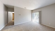 This single-floor residence offers a practical and comfortable layout across two bedrooms and two bathrooms. The living area is carpeted and features a sliding glass door fitted with vertical blinds, allowing natural light to filter in while providing a view of the outdoors. A wall-mounted thermostat and ceiling ventilation keep the space climate-controlled throughout.

The kitchen is well-equipped with white shaker-style cabinetry, granite-look countertops, a black electric range with an overhead ventilation hood, and a stainless steel sink — all set atop warm hardwood-style flooring that adds a rich contrast to the clean white finishes.

The primary bedroom is a generously sized retreat featuring plush carpeting, a ceiling fan with light fixture, and a window that brings in natural light. The second bedroom is similarly carpeted with neutral gray walls and direct hallway access.

Both bathrooms feature hardwood-style flooring and white fixtures. One bathroom includes a full tub-shower combo with tiled surround, a white vanity with granite countertop, and a window for natural ventilation. The second bathroom offers a shower and a separate water closet area.

Additional conveniences include a dedicated laundry area and a hallway closet, completing a thoughtfully organized floor plan designed for everyday functionality.