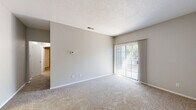 This single-floor residence offers a practical and comfortable layout across two bedrooms and two bathrooms. The living area is carpeted and features a sliding glass door fitted with vertical blinds, allowing natural light to filter in while providing a view of the outdoors. A wall-mounted thermostat and ceiling ventilation keep the space climate-controlled throughout.

The kitchen is well-equipped with white shaker-style cabinetry, granite-look countertops, a black electric range with an overhead ventilation hood, and a stainless steel sink — all set atop warm hardwood-style flooring that adds a rich contrast to the clean white finishes.

The primary bedroom is a generously sized retreat featuring plush carpeting, a ceiling fan with light fixture, and a window that brings in natural light. The second bedroom is similarly carpeted with neutral gray walls and direct hallway access.

Both bathrooms feature hardwood-style flooring and white fixtures. One bathroom includes a full tub-shower combo with tiled surround, a white vanity with granite countertop, and a window for natural ventilation. The second bathroom offers a shower and a separate water closet area.

Additional conveniences include a dedicated laundry area and a hallway closet, completing a thoughtfully organized floor plan designed for everyday functionality.
