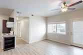 This single-story, 3-bedroom, 2-bathroom home offers a functional and modern layout designed for comfortable everyday living. The open-concept living room and kitchen area serves as the heart of the home, featuring light-toned wood-style flooring, neutral walls, and a ceiling fan with integrated lighting. A window and exterior door provide natural light and outdoor access, creating an airy atmosphere. The kitchen is efficiently designed in a galley style, showcasing rich dark walnut cabinetry, granite-style countertops, and white appliances including a refrigerator, range, and dishwasher — offering ample storage and counter space. The three bedrooms are finished with the same wood-style flooring and neutral tones, each featuring windows that bring in natural light and views of the surrounding exterior. The primary bedroom offers a comfortable footprint suited for standard bedroom furnishings. Both bathrooms are consistently appointed with dark wood vanities, granite-style countertops, undermount sinks, and full tub-shower combinations with white tile surrounds. A dedicated in-unit laundry room includes a full-size washer and dryer with overhead cabinetry for additional storage. Two hallways connect the rooms, providing a logical and easy-to-navigate floor plan throughout.