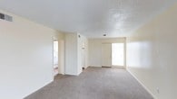 Located at 190 N Corry Field Rd in Pensacola, Florida, this single-floor residential unit offers a clean and practical layout suited for comfortable everyday living. The main living area features neutral-toned carpet flooring that extends throughout the space, contributing to a warm and cohesive feel. Walls are finished in a soft, light cream tone that reflects natural light and keeps the interior feeling open and airy. A textured popcorn ceiling adds a classic touch overhead. A front entry door with an adjacent sidelight window allows natural light to filter into the entryway, creating a welcoming transition into the living space. A partial wall or column structure divides the interior, providing a subtle separation between areas while maintaining an open feel throughout. Toward the rear of the living area, a hallway leads to additional rooms, with what appears to be a laundry or utility area visible in the background, indicating in-unit utility access. The unit is designed with functionality in mind, offering a straightforward floor plan that makes efficient use of its available space. Situated in Pensacola, FL, the location provides convenient access to the Gulf Coast, military installations, and local community resources.