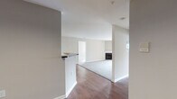 This single-floor residence offers a thoughtfully designed open layout that promotes a seamless flow between living areas. The main living and dining space is finished with rich hardwood-style flooring and features a fireplace, adding a functional and visually grounding focal point to the room. A half-wall partition defines the transition between the kitchen and the open living area, maintaining an airy, connected feel throughout.

The kitchen is well-appointed with gray cabinetry, dark granite-style countertops, a white subway tile backsplash, and a full suite of black appliances including a gas range, built-in microwave, dishwasher, and refrigerator. Hardwood-style flooring continues through the kitchen, which also benefits from overhead lighting.

A dedicated laundry area with side-by-side washer and dryer hookups is conveniently located within the unit. The bedrooms are carpeted and receive ample natural light through multiple windows with views of the surrounding exterior. Each is finished in neutral tones, offering a calm and versatile environment.

Two full bathrooms serve the unit, each featuring a tub-shower combination with white tile surround, hardwood-style flooring, a vanity with a light countertop, and chrome fixtures, providing clean and functional spaces throughout.