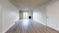 Located in Denver's Four Mile Flats neighborhood, this one-bedroom, two-bathroom residence offers a well-organized single-floor layout designed for comfortable everyday living. The living room serves as the heart of the home, featuring light wood-style flooring, a textured ceiling, and a corner fireplace with a clean white surround. A wall-mounted AC unit provides climate control, while sliding glass doors flood the space with natural light and open directly onto a private balcony with tree-lined views. The adjoining dining area transitions naturally into the galley-style kitchen, which is equipped with light wood cabinetry, dark granite-look countertops, a full suite of black appliances including a refrigerator, electric range, microwave, and dishwasher, and durable wood-style flooring. The bedroom is a calm, well-proportioned retreat finished with plush carpeting, a baseboard heater, a bright window with blinds, and a sliding-door closet. Two bathrooms serve the unit, one of which features a full tub-shower combination with stone-tiled surround walls. A hallway connects the main rooms efficiently, completing a thoughtfully arranged floor plan suited to a range of lifestyles.