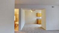 Located at 300 Hidenwood Place in Newport News, Virginia, this single-floor residence offers a practical and comfortable layout designed for easy living. The main living area is finished with wall-to-wall carpeting, creating a warm and inviting atmosphere, and is equipped with a ceiling fan that promotes air circulation throughout the space. An open-concept design connects the living area directly to the kitchen, which features warm-toned wood cabinetry, ample upper and lower storage, and a countertop workspace suitable for everyday meal preparation. The seamless flow between these two areas makes the space feel open and functional. A full bathroom is accessible from the living area and includes a toilet, sink with vanity, and a tiled shower/tub combination, providing all essential amenities. The neutral color palette used throughout — from the light walls to the carpeted floors — lends a clean, versatile backdrop well-suited to a variety of décor styles. The overall layout is efficient and cohesive, making this single-story residence a straightforward and comfortable option in the Hidenwood neighborhood of Newport News.