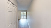 Located at 3230 SW Archer Rd in Gainesville, FL, this single-floor, one-bedroom, one-bathroom unit offers a thoughtfully designed layout that maximizes its cozy footprint. The open kitchen is a functional highlight, featuring crisp white cabinetry, a soft blue tile backsplash, light wood-style flooring, and a full suite of stainless steel appliances including a refrigerator, electric range, microwave, and dishwasher. A textured ceiling with flush lighting adds character overhead. The kitchen flows naturally into the living area, which is brightened by large sliding glass doors and a wide window that invite generous natural light and provide views of the surrounding greenery. A ceiling fan overhead enhances comfort in this shared living space, which also offers direct access to a private balcony. The bedroom is a comfortable retreat, carpeted for warmth and equipped with a ceiling fan, two closets, and easy access to hallway storage. The bathroom is clean and straightforward, featuring a full tub-and-shower combination with chrome fixtures. Throughout the unit, the light-toned palette and wood-style flooring create a bright, cohesive ambiance well-suited for everyday living.
