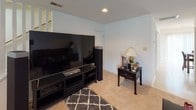 Located at 101 Mallard Ct in Greenwood, South Carolina, this two-story home offers a well-organized layout spread across two levels, as revealed by the overhead floorplan view. The main level features a functional kitchen equipped with warm oak cabinetry, a coil-element range, and a full-size refrigerator, providing ample storage and counter space. Adjacent to the kitchen, the dining area is highlighted by a striking stone-tile top table accompanied by leather chairs and pendant lighting, creating an elegant setting for meals. The living room is a comfortable gathering space with plush carpeting, recessed lighting, and a large window that invites natural light, furnished with a full leather seating arrangement. A dedicated media area is also present, configured for home entertainment with built-in shelving and carpet underfoot. The upper level hosts multiple bedrooms, each carpeted and featuring windows with blinds and curtains for light control. One bedroom includes a door with direct exterior access, adding convenience. The primary bathroom is equipped with a double-sink vanity, oak cabinetry, a large mirror with strip lighting, and a separate shower area. Throughout the home, neutral wall tones and consistent carpeting create a cohesive, understated aesthetic.