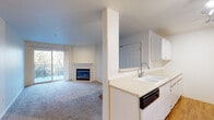 Located at 14700 SW Beard Rd in Beaverton, Oregon, this single-floor unit offers a well-designed, open layout that maximizes functionality and comfort throughout. The living area is generously proportioned, anchored by a classic tile-surround fireplace that serves as a focal point of the room. Soft wall-to-wall carpeting adds warmth underfoot, while a sliding glass door opens directly onto a private balcony overlooking lush, mature trees — bringing the natural beauty of the Pacific Northwest indoors. The kitchen is efficiently laid out with ample white cabinetry, light countertops, wood-look flooring, and a full suite of appliances including a refrigerator, electric range, built-in microwave, and dishwasher. A peninsula counter connects the kitchen to the living space, creating a seamless, open-concept flow. The bedrooms are comfortably sized with plush carpet and large windows that frame verdant outdoor views, filling each room with natural light. One bedroom provides convenient access to the in-unit laundry closet, which houses a full-size washer and dryer. The bathroom features a tub and shower combination with sliding glass doors, a wide vanity, and hardwood-style flooring. Clean, neutral tones throughout lend the space a bright and inviting ambiance.