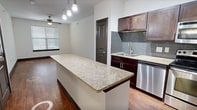This contemporary 610 square foot apartment in Irving, Texas, offers a harmonious blend of style and functionality. The open-concept layout maximizes the use of space, creating a seamless flow between living areas. The kitchen is a highlight, boasting rich wood cabinetry, sleek stainless steel appliances, and a stylish tile backsplash. Granite countertops and a breakfast bar add both elegance and practicality.

The spacious bedroom, measuring 160 square feet, features plush carpeting and is equipped with a ceiling fan for comfort. Large windows allow for ample natural light, while horizontal blinds offer privacy when needed. The apartment includes a well-designed closet with built-in shelving and drawers, providing ample storage space.

Throughout the apartment, you'll find a cohesive design aesthetic with dark wood doors, baseboards, and trim contrasting beautifully against light walls. The main living area showcases gleaming hardwood floors, while the bedroom's carpeting adds warmth and comfort. Recessed lighting and modern light fixtures illuminate the space effectively. This thoughtfully designed apartment offers a perfect balance of comfort and style in a compact, efficient layout.