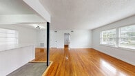 This thoughtfully designed single-floor residence offers a seamless blend of classic character and modern updates across a comfortable, well-organized layout. Polished hardwood floors flow throughout the main living areas and bedroom, reflecting natural light and adding warmth to the bright, white-walled interior.

The open-concept kitchen and living area serves as the heart of the home. The updated kitchen is a standout feature, showcasing sage green cabinetry, stainless steel appliances including a full-size refrigerator and gas range, and a striking peninsula topped with a white marble-look quartz countertop. A gold-toned faucet and modern sputnik-style light fixtures add contemporary flair, while multiple windows flood the space with natural light.

The living area is spacious and open, featuring a textured ceiling and a wide bank of windows that bring in ample daylight and views of the surrounding neighborhood.

The bedroom is a comfortably sized, quiet retreat with its own closet, hardwood floors, and natural light from a window. A utility room provides practical additional storage or laundry space.

The bathroom is tastefully renovated, featuring large-format grey wall tiles, hexagonal floor tiles, a soaking tub with a handheld shower, a pedestal sink with matte black fixtures, and a bright window for natural ventilation.