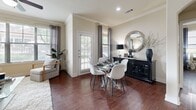 Located in Austin, TX, this thoughtfully designed one-bedroom, two-bathroom residence offers a comfortable and functional single-floor layout. Rich dark wood-style flooring flows consistently throughout, anchoring the warm, neutral color palette that unifies the space.

The open-concept living area is generously proportioned, bathed in natural light from large windows dressed with layered blinds and curtains that offer outdoor views of the surrounding community. Crown molding adds a refined architectural detail to the living room.

The kitchen is a standout feature, showcasing dark espresso cabinetry, granite-style countertops, stainless steel appliances, a breakfast bar with pendant lighting, and a charming arched passageway that adds character to the layout.

The primary bedroom is a comfortable retreat with a ceiling fan, a walk-in closet equipped with multi-tier wire shelving, and a window that invites natural light. Both bathrooms feature dark vanity cabinetry, granite-style countertops, soaking tubs with tile surrounds, and framed mirrors.

A dedicated laundry room with side-by-side washer and dryer units and built-in shelving adds everyday convenience. The walk-in closet provides ample organized storage, completing this well-rounded Austin residence.