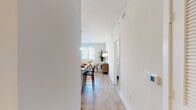 This single-floor residence is designed with a clean, contemporary aesthetic that emphasizes light and openness. Wood-look tile flooring flows throughout the main living areas, creating a cohesive and warm foundation underfoot. Neutral white walls and natural light from multiple windows contribute to the bright, airy atmosphere found in every room.

The kitchen serves as a central highlight, featuring white cabinetry, granite countertops, a subway tile backsplash, stainless steel appliances, and a large island with pendant lighting overhead — ideal for both meal preparation and casual dining. Adjacent to the kitchen, the dining area offers a comfortable, dedicated space with natural light and room for a full table setting.

The living room is understated and functional, with ample wall space and a window that draws in natural light. The hallway connects the living spaces to multiple bedrooms, each offering closet storage and windows. The primary bedroom is generously sized with room for a dresser and large bed. Two bathrooms serve the residence: one featuring a tub-shower combo with granite vanity, and a second en-suite bath with a glass-enclosed walk-in shower and matching granite countertop. A smart thermostat is also present near the entry hallway.