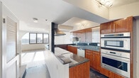 Located at 800 S Wells Street in Chicago's South Loop neighborhood, this multi-level residence spans three floors and showcases a blend of modern design and urban sophistication. The gourmet kitchen is a standout feature, outfitted with rich, high-gloss wood cabinetry, dark granite countertops, stainless steel appliances including a double wall oven, built-in microwave, side-by-side refrigerator, and dishwasher. A central island with a cooktop and overhead ventilation hood adds both functionality and visual appeal, while polished dark tile flooring completes the culinary space. The kitchen flows openly into adjacent living areas, enhancing the sense of spaciousness throughout. Bedrooms are finished with warm hardwood flooring, generous built-in closet storage, and clean white walls that maximize natural light. A striking architectural detail is the curved, multi-panel window wall found in one of the living spaces, framing sweeping views of the Chicago skyline and cityscape. Bathrooms include a full bath with a soaking tub, textured tile surround, and chrome fixtures, as well as a clean, minimalist powder room. The three-floor layout, visible in the dollhouse view, features an elegant internal staircase connecting the levels. This residence offers a refined urban living experience in one of Chicago's most dynamic neighborhoods.