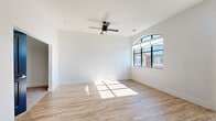 Located at 205 S High St in the heart of downtown Columbus, Ohio, this one-bedroom, one-bathroom unit offers a well-planned layout with modern finishes throughout. The combined kitchen and living area forms the centerpiece of the space, characterized by crisp white walls, hardwood-style flooring, and abundant natural light streaming through a distinctive arched window and a set of French doors that frame views of the surrounding urban streetscape. A ceiling fan adds comfort to the airy living area.

The kitchen is outfitted with warm wood cabinetry, white quartz countertops, white tile backsplash, and a full suite of stainless steel appliances including a refrigerator, electric range, over-the-range microwave, and dishwasher — providing a functional and stylish cooking space.

A hallway connects the main living area to the private bedroom, which features plush carpet flooring and a dedicated closet. The bathroom is finished with a wood-toned vanity, white countertop, a large mirror with contemporary light fixtures, and a glass-enclosed walk-in shower with tile surround. The bold blue bathroom door adds a distinctive design accent. Multiple hallways contribute to a sense of flow and accessibility throughout the unit.