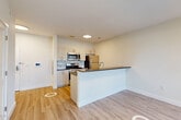 This well-appointed one-bedroom, one-bathroom residence at 72 South Essex Avenue in Orange, NJ offers a thoughtfully designed open-concept layout with modern finishes throughout. The combined living, dining, and kitchen area forms the heart of the home, featuring light wood-look flooring, crisp white walls, and recessed lighting that together create a bright, welcoming atmosphere. The kitchen is equipped with stainless steel appliances — including a refrigerator, range, and microwave — complemented by light wood cabinetry, a tile backsplash, dark countertops, and a peninsula that provides additional prep space and a natural divide between the kitchen and living areas. Large black-framed windows invite ample natural light and offer views of the surrounding neighborhood. The bedroom is a comfortable, well-lit retreat with its own oversized window and direct access to a generous walk-in closet outfitted with wire shelving and additional storage. A second closet provides even more organizational flexibility. The full bathroom features large-format gray tile flooring, a dark wood vanity with a mirror, and clean, modern fixtures. Additional conveniences include a dedicated laundry area and a utility room, rounding out this efficiently designed and move-in-ready home.