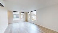 This well-designed two-story residence offers 2 bedrooms and 2 bathrooms across two efficiently laid-out floors. The main level centers around an open-concept kitchen and living area bathed in natural light from large, floor-to-ceiling windows that frame views of the surrounding neighborhood. The kitchen features stainless steel appliances, white upper cabinetry paired with warm wood lower cabinets, a white quartz peninsula with pendant lighting overhead, and recessed lighting throughout. Light hardwood flooring flows seamlessly through the main living areas, enhancing the bright, airy ambiance. A wall-mounted mini-split unit provides climate control on the lower level. The upper floor houses both bedrooms, each finished with plush carpeting and generous windows. The primary bedroom offers a spacious walk-in closet with wire shelving systems. A second bedroom features a large picture window overlooking mature trees and the surrounding area. Two full bathrooms include a single-sink vanity with wood cabinetry, a full soaking tub with shower, and a large mirror. Additional features include three closets for ample storage, a dedicated utility room, and a staircase connecting the two floors. The overall aesthetic is clean, contemporary, and move-in ready.