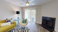 This single-story residence at 6550 150th Ave N in Largo, Florida offers a well-organized layout with wood-look flooring throughout and a consistent neutral color palette that creates a cohesive, comfortable atmosphere.

The living room serves as the central gathering space, anchored by a striking dark tile-surround fireplace and a ceiling fan overhead. Vertical blinds cover full-height sliding glass doors that allow natural light to filter in and provide views of the surrounding greenery. The textured ceiling adds a classic residential character to the room.

The galley-style kitchen features white cabinetry, stainless steel appliances including a refrigerator and range, and ample counter space along both sides, making efficient use of the available area. Light-toned flooring carries through the kitchen, reinforcing the clean aesthetic.

Multiple bedrooms offer comfortable accommodations, each equipped with ceiling fans, natural light through blinds-covered windows, and wood-look flooring. Several rooms provide views of tropical palm trees outside, reflecting the Florida setting.

The bathrooms include a tub/shower combination with white tile surround, a vanity with a light countertop, and a large mirror, maintaining the clean and functional design found throughout the home.