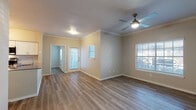 This single-story unit is designed with a clean, modern aesthetic and consistent wood-look luxury vinyl plank flooring throughout. The open-concept living and dining area is bright and welcoming, featuring crown molding, a ceiling fan with integrated lighting, and multiple windows with blinds that allow natural light to filter through. A front entry door provides direct access to the living space.

The kitchen is well-appointed with white shaker-style cabinetry, gray quartz countertops, a subway tile backsplash, and a full suite of stainless steel appliances, including a refrigerator, electric range, microwave, and dishwasher. A peninsula with an undermount sink adds additional prep and counter space.

The unit includes two bedrooms, each equipped with ceiling fans and generous closet space. One bedroom features a walk-in closet, while the other benefits from ample natural light through a large window. Both bathrooms maintain a clean, minimal design with wood-toned vanities, white tiled tub-shower combinations, and light-toned flooring, providing a cohesive and functional finish throughout the space.