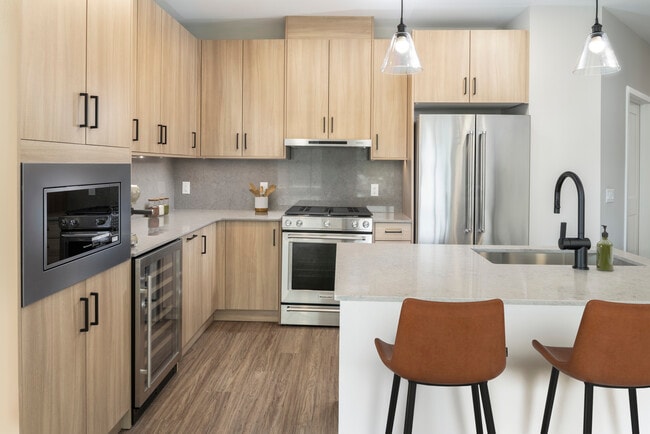 Signature Collection kitchen with stainless steel appliances (wine fridge included), quartz countertops, quartz tile backsplash, oak cabinetry, and hard-surface flooring - Avalon Parsippany
