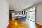 Located in Chicago's vibrant West Loop neighborhood, this well-appointed 2-bedroom, 2-bathroom residence offers a thoughtfully designed single-floor layout. Warm hardwood flooring flows throughout the living areas, hallway, and bedrooms, creating a cohesive and inviting atmosphere accented by crown molding and recessed lighting.

The open-concept kitchen is a standout feature, showcasing slate-gray cabinetry, a subway tile backsplash, stainless steel appliances including a full-size refrigerator, a center island with granite countertops, and pendant lighting. Sliding glass doors from the living and dining area lead to a private balcony, filling the space with natural light and providing outdoor access.

The primary bedroom is generously sized and includes a walk-in closet with built-in shelving and hanging systems. The second bedroom also benefits from hardwood floors, a ceiling fan, and natural light. Three closets in total ensure ample storage throughout.

Both bathrooms are finished with large-format tile, granite-topped vanities, and clean white cabinetry. The primary bath features a dual-sink vanity, while the second bath offers a tub-shower combination with full tile surround. A dedicated laundry area and utility room add further convenience to this well-rounded Chicago residence.
