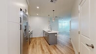 Located at 500 W Camelback Rd in Phoenix, Arizona, this well-appointed 2-bedroom, 2-bathroom residence offers a thoughtfully designed single-level layout. The open-concept kitchen and living area serves as the heart of the home, featuring a central island with a built-in sink, white quartz countertops, and sleek gray cabinetry accented with matte black hardware. Stainless steel appliances — including a gas range, wall oven, microwave, and refrigerator — are complemented by a stylish tile backsplash. Pendant lighting above the island adds a modern touch. Light wood-style flooring flows throughout the main living areas, creating a warm and cohesive aesthetic. The living room benefits from multiple windows fitted with white blinds, allowing for generous natural light. Both bedrooms are carpeted and offer a quiet, comfortable retreat, with the primary bedroom featuring access to a dedicated closet complete with built-in shelving and hanging rods. The two bathrooms are finished in a clean, contemporary style — one featuring a glass-enclosed walk-in shower with white subway tile and light wood-style flooring. The overall ambiance is bright, modern, and move-in ready, reflecting a crisp, neutral palette throughout.