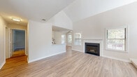 Located at 9807 Gable Ridge Terrace in Rockville, MD, this two-floor residence offers a thoughtfully designed layout across a generously sized main level and a more intimate upper floor. The main level serves as the heart of the home, anchored by a bright, open living area with striking vaulted ceilings that amplify the sense of space. Light wood-style flooring runs throughout, complementing the neutral color palette. A fireplace with a classic white mantel provides a focal point in the living room, while multiple windows allow abundant natural light. The kitchen features a galley-style configuration with white shaker cabinetry, quartz countertops, stainless steel appliances including a gas range, microwave, and refrigerator, and direct access to a full bathroom. A half bathroom on the main level offers added convenience. The staircase, finished with warm wood railings, connects to the upper floor, where the primary bedroom is carpeted and filled with natural light from large windows. A spacious walk-in closet with wire shelving provides ample storage. The upper level also includes a full bathroom with a tub-shower combination and a white vanity. The overall ambiance is clean, bright, and move-in ready.