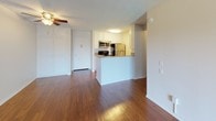 This single-story unit in Garden Grove, CA offers a well-organized layout with a mix of hardwood flooring and plush carpeting throughout its living spaces. The open-concept living and dining area features rich, dark hardwood floors that extend toward a sliding glass door with vertical blinds, opening to a balcony with outdoor views of surrounding greenery. A textured ceiling and ceiling fan add functional character to the space.

The kitchen is defined by a wraparound peninsula that separates it from the main living area, providing a natural pass-through design. White cabinetry lines the walls, complemented by granite-style countertops and a full suite of stainless steel appliances, including a refrigerator, range, and microwave.

The carpeted bedroom areas offer a quieter, softer environment. One room features its own ceiling fan and a window dressed with vertical blinds, allowing natural light to filter in. The bathroom is well-appointed with a long vanity topped with granite-style counters, white cabinetry with ample drawer storage, wood-look flooring, a large mirror, and a tub/shower combination. The overall aesthetic is clean and neutral, with white walls and bright lighting creating a fresh, move-in-ready atmosphere.