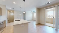 This single-floor residence offers a thoughtfully designed open-concept layout that seamlessly connects the kitchen, dining, and living areas. The kitchen is a standout feature, showcasing rich wood-tone cabinetry, a white subway tile backsplash, stainless steel appliances including a range, microwave, refrigerator, and dishwasher, all complemented by expansive granite countertops. A large central island with an undermount sink and a modern pendant light serves as both a functional workspace and a natural gathering point. Light wood-style flooring flows throughout the main living areas, creating a bright and airy atmosphere, while a ceiling fan keeps the open living space comfortable. The bedroom is generously proportioned, featuring plush carpeting, natural light from multiple windows with views of the surrounding neighborhood, and access to a spacious walk-in closet outfitted with built-in shelving and dual hanging rods. Two bathrooms provide distinct functionality: one features a tiled walk-in shower with a sliding glass door, a wood-framed vanity with granite countertops, and light flooring; the second offers a full tiled tub-shower combo, a matching granite vanity, and a framed mirror. The overall design is clean and contemporary, with neutral tones throughout.