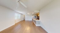 This single-floor residence presents a thoughtfully designed layout that balances open communal spaces with private retreats. The living area is expansive and airy, featuring light-toned hardwood-style flooring, a ceiling fan, and track lighting overhead. Natural light filters in through slatted blinds, creating a bright and welcoming atmosphere. The space flows seamlessly toward the kitchen, which is defined by a peninsula counter with a quartz-style surface and an undermount sink. The kitchen itself is outfitted with light wood cabinetry, a full suite of stainless steel appliances including a side-by-side refrigerator, electric range, and microwave, and is finished with matching light flooring.

The bedrooms are carpeted for comfort and each features a ceiling fan and generous window coverage, providing good natural light and outdoor views. One bedroom includes an attached hallway leading to additional closet or storage space. The bathrooms are finished in a modern style — one includes a wood-toned vanity with a white countertop, large mirror, and glass-enclosed shower, while another features a white-tiled tub and shower combination with brushed nickel fixtures. A carpeted staircase with a white rail connects to an additional level.
