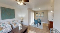 This single-floor residence offers a thoughtfully designed layout that balances comfort and functionality throughout. The open-concept living and dining area is anchored by wood-look flooring, a ceiling fan with light fixture, and recessed lighting, creating a bright and welcoming atmosphere. Large windows dressed with blinds allow ample natural light to fill the space, while a sliding glass door with vertical blinds provides additional brightness to the dining area.

The kitchen is a standout feature, boasting warm-toned wood cabinetry, granite countertops, a central island with bar seating, pendant lighting, and a full suite of stainless steel appliances including a refrigerator, range, and over-the-range microwave. Recessed lighting and a window above the sink further enhance this well-equipped culinary space.

Both bedrooms are generously sized, each fitted with plush carpeting, ceiling fans, and ample natural light from large windows. The primary bedroom includes a walk-in closet, providing excellent storage. The bathrooms echo the kitchen's refined finishes with granite-topped vanities, wood cabinetry, and wood-look flooring. A convenient entryway area connects the main spaces, completing this cohesive and comfortable single-story home.