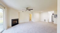 This well-designed 2-bedroom, 2-bathroom single-floor home at 6808 Clubhouse Dr in Harrisburg, PA offers a comfortable and functional layout. The open-concept living and dining area is a standout, featuring plush carpeting, a ceiling fan, and a sleek fireplace framed by a sliding glass door that fills the room with natural light and provides views of the outdoors. The kitchen is thoughtfully appointed with gray shaker-style cabinetry, light granite countertops, stainless steel appliances including a gas range, microwave, refrigerator, and dishwasher, all set over light wood-look flooring. A pass-through window connects the kitchen to the living area, enhancing the open feel. Both bedrooms are generously sized, carpeted, and include ceiling fans and windows that invite natural light. The bathrooms feature dark wood vanities, tile flooring, and clean, classic finishes. Two closets provide ample storage throughout. The attached garage offers additional storage with built-in shelving and an automatic opener. Neutral tones and clean lines throughout create a bright, welcoming ambiance.