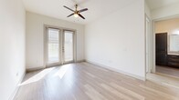 Located at Greenside Dr in Richardson, TX, this well-appointed 2-bedroom, 2-bathroom single-floor residence offers a thoughtfully designed open-concept layout. The combined living, dining, and kitchen area serves as the heart of the home, featuring light wood-tone flooring that flows throughout. The kitchen stands out with rich dark cabinetry, a herringbone-style tile backsplash, granite countertops, stainless steel appliances, and a central island with a built-in sink and pendant lighting above — ideal for both cooking and entertaining. The primary bedroom is generously sized and connects to a well-appointed en suite bathroom complete with granite-topped dark wood vanity, large mirror, tiled walk-in shower, and porcelain tile flooring. A spacious walk-in closet provides ample storage. The second bedroom benefits from natural light through large windows with blinds and comfortable wood-tone flooring with a ceiling fan above. Both bathrooms reflect a consistent, modern aesthetic. Additional highlights include three closets, an in-unit laundry area, and a private patio. The clean white walls, modern panel doors, and cohesive finishes throughout create a bright, contemporary ambiance.