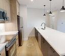 This contemporary 770-square-foot, one-bedroom, one-bathroom unit at 2310 Richmond Street in London, Ontario, offers a thoughtfully designed single-floor layout with modern finishes throughout. Light hardwood flooring flows consistently across all living areas, creating a cohesive and bright atmosphere.

The open-concept kitchen and living room is a standout feature, anchored by a large island with a white quartz countertop, navy-blue base, and matte black pendant lighting. Light wood cabinetry, stainless steel appliances — including a range, over-the-range microwave, and refrigerator — and white countertops complete the kitchen. The living room offers recessed lighting and a sliding glass door providing direct outdoor access and natural light.

The 130-square-foot bedroom features a large black-framed window with outdoor views and a distinctive blue accent wall. Two closets provide ample storage, including one with wire shelving and hanging rods.

The bathroom is finished with a clean, modern aesthetic, featuring a tub-shower combination with white subway tile surround, matte black fixtures, a wood-toned vanity with white countertop, and light tile flooring. Recessed lighting and a curved shower rod complete the space. The unit combines functional design with contemporary styling throughout.