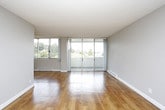 This single-floor residence offers a thoughtfully laid-out living space with a clean, neutral aesthetic throughout. The open-concept living and dining area is anchored by warm hardwood flooring and flanked by large sliding glass doors that lead to a balcony, flooding the space with natural light and providing outdoor views of the surrounding neighbourhood. A ceiling fan adds both function and character to the living area.

The kitchen is efficiently designed in a galley-style layout, featuring light wood cabinetry, grey subway tile backsplash, white countertops, and stainless steel appliances including a refrigerator, dishwasher, and built-in microwave. A stainless steel sink and ample upper and lower cabinet storage complete the space.

The bedroom offers plush grey carpeting, a large window with expansive outdoor views, and a baseboard heating unit. The space is bright and generously proportioned, with a textured ceiling consistent throughout the unit.

The bathroom is finished with a wide vanity featuring light wood cabinetry, multiple drawers, a white countertop with an undermount sink, and a large mirrored medicine cabinet with overhead lighting. A separate tub and shower area complete the bathroom. Hardwood flooring continues into the hallway and bathroom entry, tying the overall design together with a warm, cohesive feel.