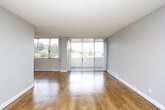 This single-floor residence offers a thoughtfully laid-out living space with a clean, neutral aesthetic throughout. The open-concept living and dining area is anchored by warm hardwood flooring and flanked by large sliding glass doors that lead to a balcony, flooding the space with natural light and providing outdoor views of the surrounding neighbourhood. A ceiling fan adds both function and character to the living area.

The kitchen is efficiently designed in a galley-style layout, featuring light wood cabinetry, grey subway tile backsplash, white countertops, and stainless steel appliances including a refrigerator, dishwasher, and built-in microwave. A stainless steel sink and ample upper and lower cabinet storage complete the space.

The bedroom offers plush grey carpeting, a large window with expansive outdoor views, and a baseboard heating unit. The space is bright and generously proportioned, with a textured ceiling consistent throughout the unit.

The bathroom is finished with a wide vanity featuring light wood cabinetry, multiple drawers, a white countertop with an undermount sink, and a large mirrored medicine cabinet with overhead lighting. A separate tub and shower area complete the bathroom. Hardwood flooring continues into the hallway and bathroom entry, tying the overall design together with a warm, cohesive feel.