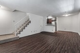 This two-story residence in the 90066 neighborhood of Los Angeles offers a thoughtfully designed layout spread across two floors. The main level features an open living area with rich hardwood-style flooring that extends throughout, bathed in natural light from multiple plantation-shuttered windows. A staircase connects the levels, adding an architectural focal point to the living space.

The kitchen is positioned at the edge of the main living area and is accessible via a peninsula counter with granite-style surfaces. Dark mahogany cabinetry provides generous storage, complemented by a stainless steel refrigerator, range, and built-in microwave. A tile backsplash adds a refined finishing detail.

Upstairs, the bedrooms are carpeted for comfort and feature neutral-toned walls. One bedroom includes mirrored sliding closet doors, offering practical storage. Bathrooms are well-appointed, with granite-topped vanities, medicine cabinet mirrors, and glass-enclosed shower fixtures. A full bathroom with a tub-shower combination is accessible from one of the bedrooms.

Throughout the residence, textured ceilings, recessed ventilation, and consistent trim details contribute to a clean, functional aesthetic suited to everyday living in Los Angeles.