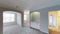 Located at 100 Village Crossing Dr in Chapel Hill, NC, this single-floor home offers a thoughtfully designed interior that balances classic architectural details with a clean, contemporary aesthetic. The living areas are defined by graceful arched doorways that create a sense of flow and openness between rooms, while soft neutral wall tones and plush carpeting lend a warm, inviting ambiance throughout. A standout feature is the built-in arched niche with white cabinetry and a granite-topped countertop, providing both a decorative focal point and practical storage. Crown molding adds a refined finishing touch to the main living spaces. Natural light filters through multiple windows, brightening the interior and highlighting the cohesive color palette of grays and whites. The dining or breakfast area is accentuated by a pendant light fixture, lending a touch of elegance to everyday living. The home's single-level layout promotes ease of movement and accessibility, making it as functional as it is attractive. Overall, the space presents a polished, well-maintained interior with architectural character and a welcoming atmosphere suited to a variety of lifestyles.