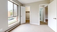 Located at 8955 Wyandotte St E in Windsor, Ontario, this two-bedroom, one-bathroom unit offers a practical and well-organized single-floor layout. The interior is finished with neutral-toned walls and wall-to-wall carpeting throughout the living and bedroom areas, creating a consistent and understated aesthetic.

The generously sized primary bedroom is a standout feature, offering substantial square footage along with a dedicated walk-in closet and a window that brings in natural light and views of the surrounding greenery. Baseboard heating is present in the bedrooms, providing efficient and consistent warmth. The second bedroom maintains the same neutral palette and carpeted flooring.

The full bathroom is clean and functional, featuring white subway tile surrounding a bathtub with an overhead shower, white tile flooring, and a vanity with a grey countertop.

The main living area is bright and open, highlighted by a sliding glass door that leads to an outdoor space and frames views of mature trees outside. A baseboard heater runs along the exterior wall, and the space is finished with the same light carpeting found throughout.

Two closets provide ample storage, and a dedicated entrance completes the layout. The overall design is clean, minimal, and move-in ready.