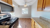 This upgraded two-bedroom, one-and-a-half-bath apartment in Ann Arbor, Michigan, offers a well-designed single-floor layout with a thoughtful mix of functional and aesthetic upgrades throughout. The kitchen is outfitted with warm honey-toned cabinetry, granite countertops, stainless steel appliances including a range with microwave above, and a dishwasher. Rich hardwood-style flooring runs through the kitchen and extends into the adjacent dining area, which features a ceiling fan with light fixture and a window providing natural light and outdoor views. A dedicated pantry closet adds convenient storage just off the kitchen.

The bedrooms are generously proportioned and finished with plush wall-to-wall carpeting and neutral tones. The primary bedroom includes crown molding and a bank of three closets offering ample storage, while the second bedroom benefits from dual windows that bring in abundant natural light. A carpeted hallway connects the private areas of the unit.

The full bathroom features tile flooring, a tiled tub-and-shower combination, and a granite-topped vanity. The half-bath is compact and well-appointed with a granite ledge countertop, tile flooring, and a framed mirror. The overall ambiance is clean, neutral, and move-in ready.