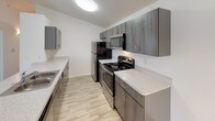 This single-floor, 2-bedroom, 2-bathroom residence offers a thoughtfully designed layout that balances comfort and functionality. The open-concept living and dining area is anchored by plush wall-to-wall carpeting and a large sliding glass door that fills the space with natural light while providing direct access to a private wooden deck with outdoor views. A pendant light fixture adds a welcoming touch to the central living zone.

The kitchen is well-equipped with a full suite of stainless steel appliances, including a refrigerator, electric range, and over-the-range microwave. Galley-style in layout, it features rich dark wood cabinetry, sparkling quartz countertops, and light wood-look flooring that extends throughout the kitchen and bathrooms, creating a cohesive aesthetic.

Both bedrooms are carpeted, well-lit with ceiling fans, and include windows that bring in natural light and outdoor views. Each room offers a calm, neutral palette ideal for a variety of uses.

The two bathrooms are finished with the same quartz countertops and dark wood vanity cabinetry found in the kitchen. One bathroom includes a full tub-shower combination, while the second features a dedicated shower area, both with light wood-look flooring and brushed nickel fixtures throughout.