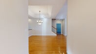This two-story home offers a well-organized layout spread across a generously sized main floor and a secondary upper level. The main floor serves as the heart of the home, featuring warm hardwood flooring throughout the living areas, a vaulted-ceiling living room with a fireplace, large arched transom windows, and a ceiling fan that fills the space with natural light and an airy ambiance. A second living area flows naturally from the main gathering space, anchored by an elegant pendant chandelier beneath a tray ceiling detail. The kitchen is outfitted with rich cherry wood cabinetry, light stone countertops, and a full suite of stainless steel appliances including a gas range, built-in microwave, and dishwasher. A staircase with a classic wood banister leads to the upper level. The spacious primary bedroom offers crown molding and plush carpeting. Additional bedrooms feature ceiling fans and carpet flooring with warm accent walls. The primary bathroom is well-appointed with tile flooring, a cherry wood vanity, a soaking tub, and a glass-enclosed walk-in shower. Three closets, a utility room, and an attached garage with a clean concrete floor and ample storage space complete this functional and comfortable home.