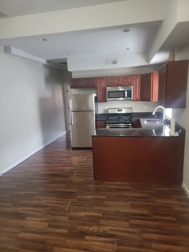 Cocina comedor con hermosas encimeras de granito, estufa de gas, lavavajillas y refrigerador de acero inoxidable. - 5201 Germantown Ave